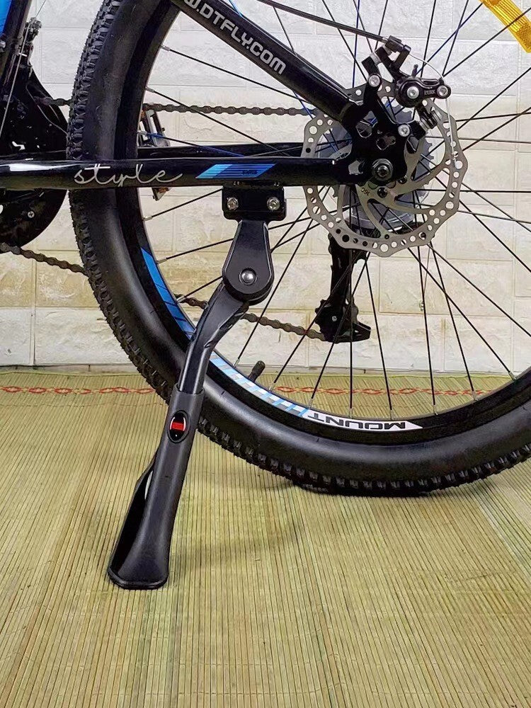 Bicycle with a black kickstand on a wooden floor.