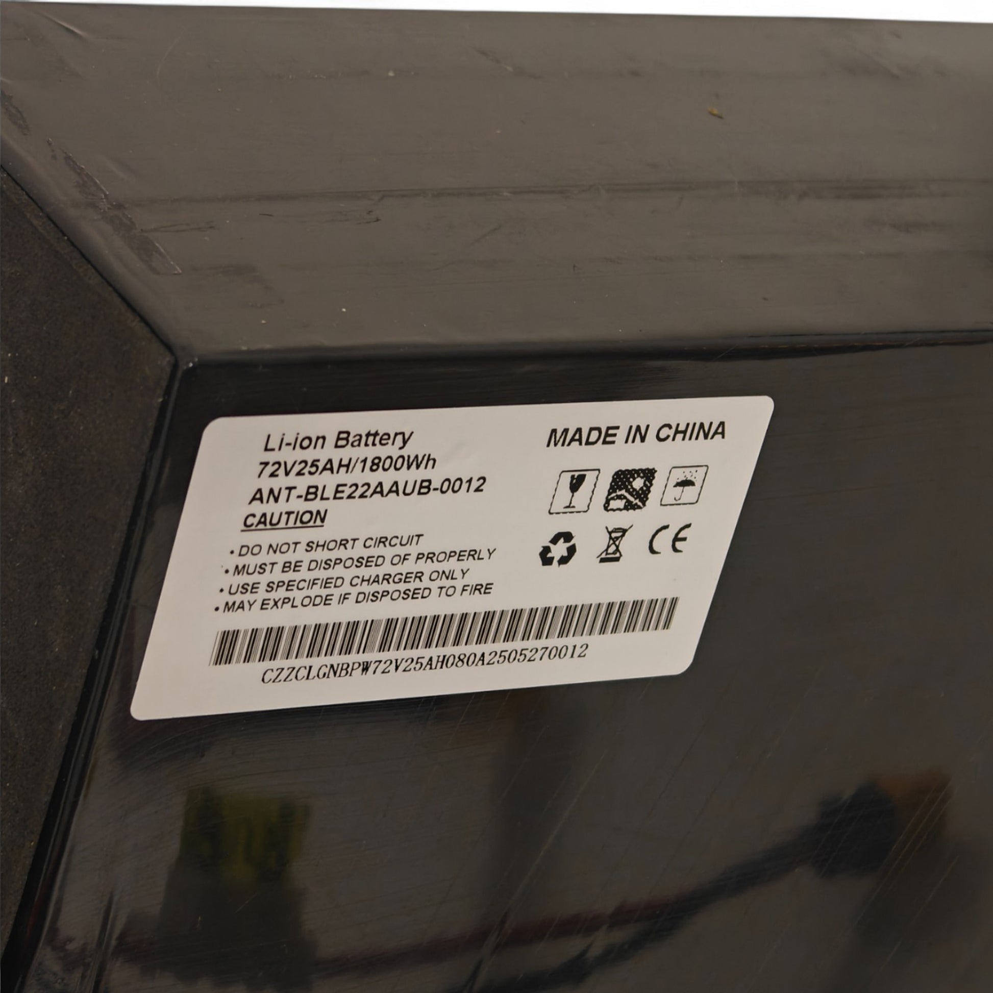 Battery label on a black surface with text and symbols